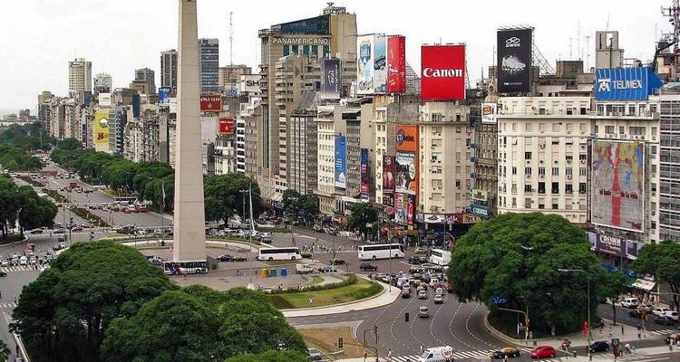 Panoramic avenue with the Obelisk of Buenos Aires towering amid vibrant billboards and bustling traffic.