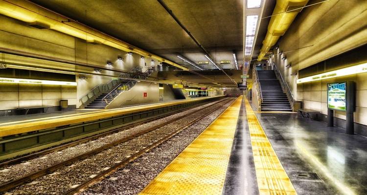 Futuristic empty metro station with yellow lighting, clean platforms, and vanishing train tracks.