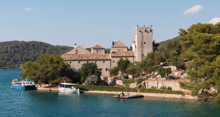 Monastère en pierre et tour sur une petite péninsule verdoyante entourée par les eaux bleues et calmes de Mljet.