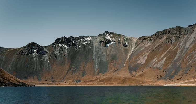 Malerischer Kratersee umgeben von steilen Vulkanhängen unter klarem Himmel am Nevado de Toluca.