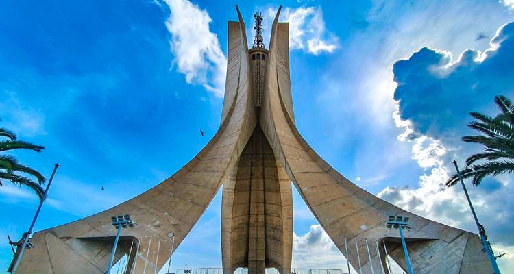 The soaring concrete arches of the Martyrs' Memorial tower against a bright blue sky.