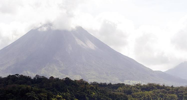 Der Arenal-Vulkan erhebt sich über dem Regenwald, wobei sein Gipfel in Wolken gehüllt ist.