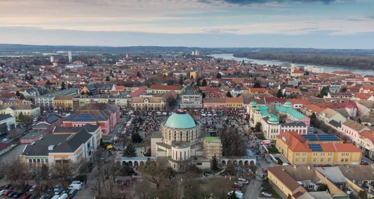 Aerial of Pécs with domed mosque in central square and river in distance.