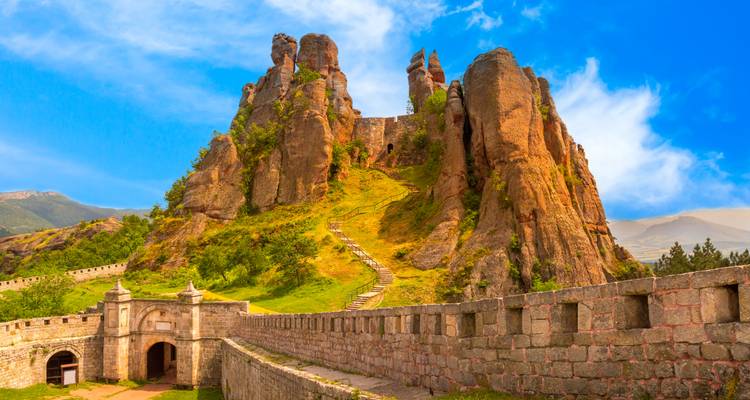 Dramatic red rock formations and fortress walls of Belogradchik set against blue sky.