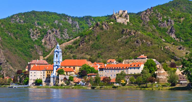 Charmant uitzicht op de rivier in Dürnstein met zijn iconische blauwe kerktorentje en de verwoeste kasteel op de heuvel.