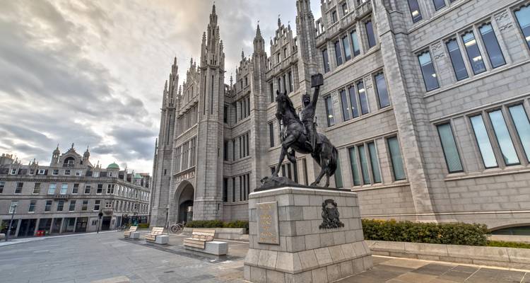 Granite façade of Aberdeen’s Marischal College with an equestrian statue of Robert the Bruce in front.