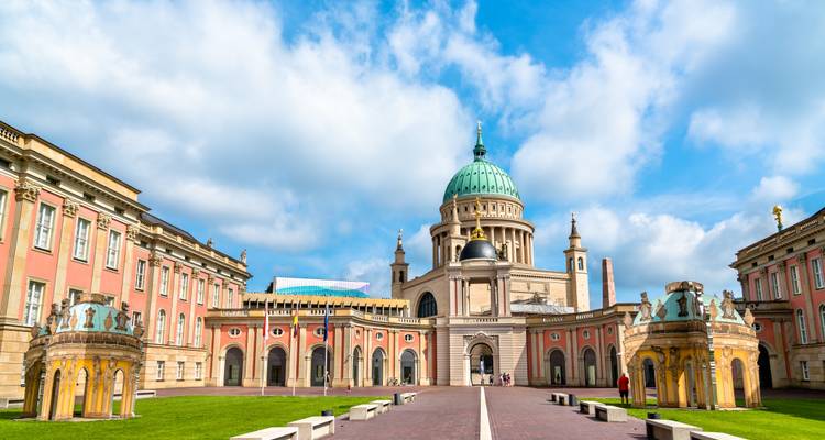 St. Nicholas Church in Potsdam with its grand copper dome framed by pink neoclassical wings and lawns.