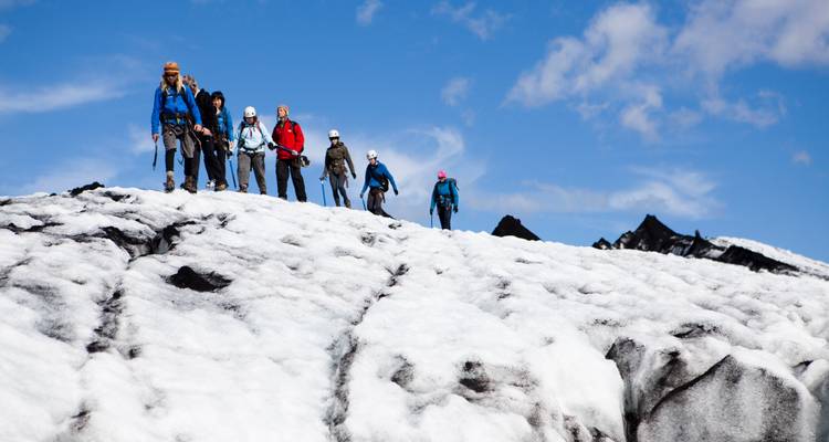 Les voyageurs munis de crampons traversent une crête de neige brillante sous un ciel bleu cobalt lors d'une randonnée glaciaire.