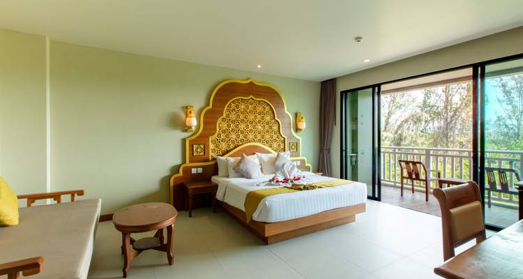 Geräumiges Zimmer im Resort mit verziertem goldenem Kopfteil, dekorativer Handtuchkunst mit Blumenmotiven und Balkontüren.