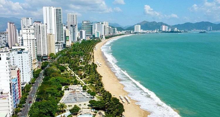 Long curving golden beach lined with palms and high-rise hotels, turquoise sea lapping the shore of Nha Trang.