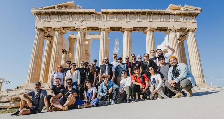 Große Reisegruppe, die vor den ikonischen Säulen des Parthenon unter klarem Himmel posiert