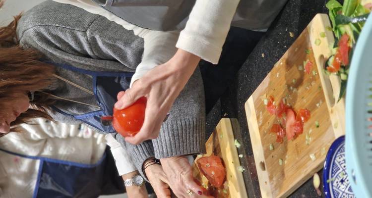 Deelnemers snijden tomaten en groenten op houten snijplanken tijdens een praktische Marokkaanse kookworkshop.