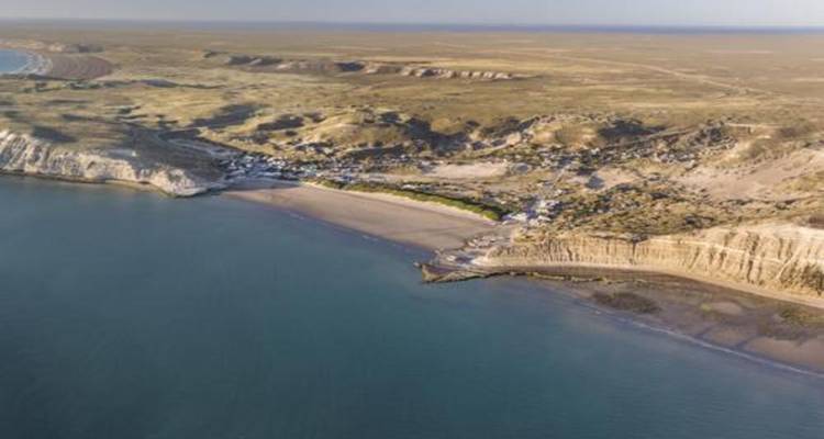 Aerial panorama of a sparsely populated coastal peninsula with beaches and cliffs.
