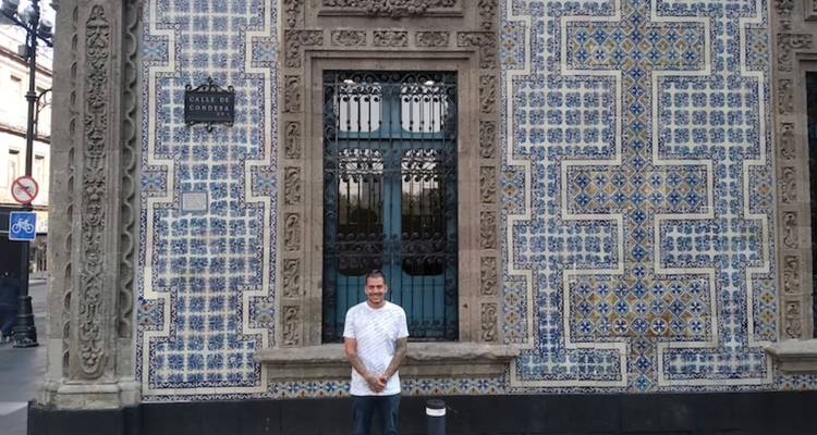 Reisender, der vor der blau-weiß gefliesten Fassade des Casa de los Azulejos in Mexiko-Stadt posiert