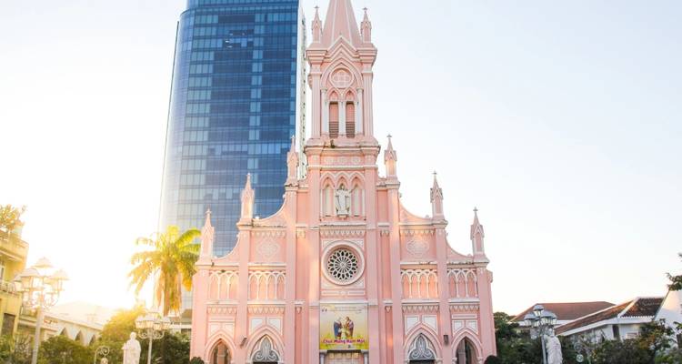Cathédrale de style gothique rose contrastant avec un gratte-ciel en verre moderne à la lumière de l'aube.