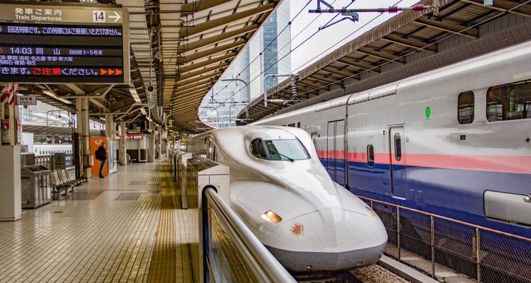 Elegante tren bala Shinkansen blanco esperando en una plataforma de estación moderna.