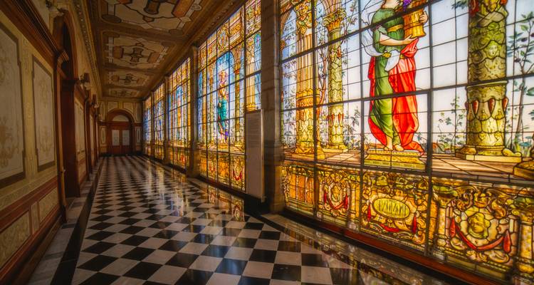 Eleganter Flur mit kunstvollen Buntglasfenstern und schwarz-weißem Schachbrettmuster-Boden in historischem Palast