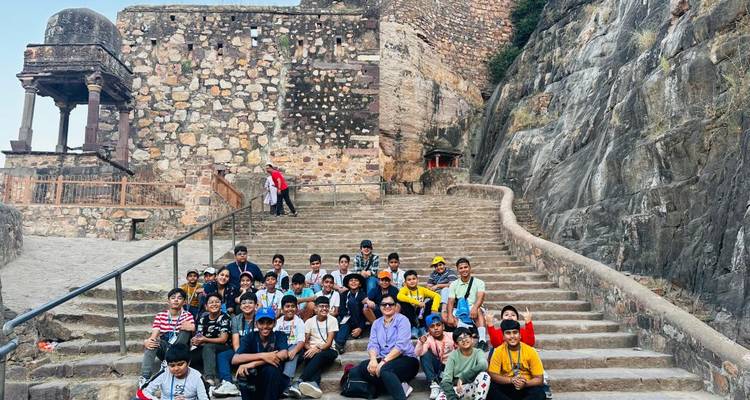 Large student group posing on stone steps of an ancient fort