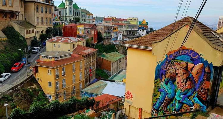 Color-splashed houses and steep alleyways in Valparaiso adorned with large murals and street art.
