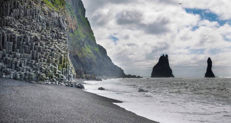 Basaltsäulen am Reynisfjara Strand mit Felsformationen im Meer.