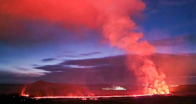 Nachtelijke vulkaanuitbarsting met een felrode lavafontein die oplicht tegen de donkere hemel