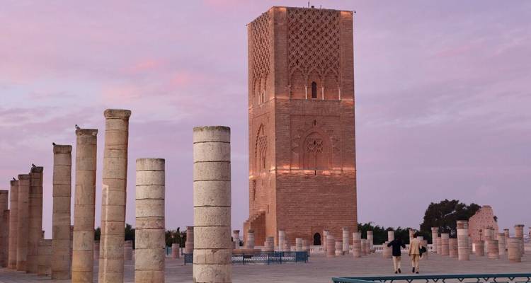 La Tour Hassan et les colonnes environnantes s'illuminent au crépuscule sous un ciel rose pastel.