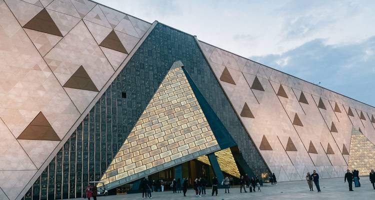Visitors entering a modern museum with triangle-patterned stone facade