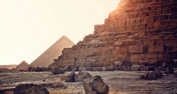 Stone blocks and weathered steps of the Great Pyramid catching warm morning light, with distant pyramids