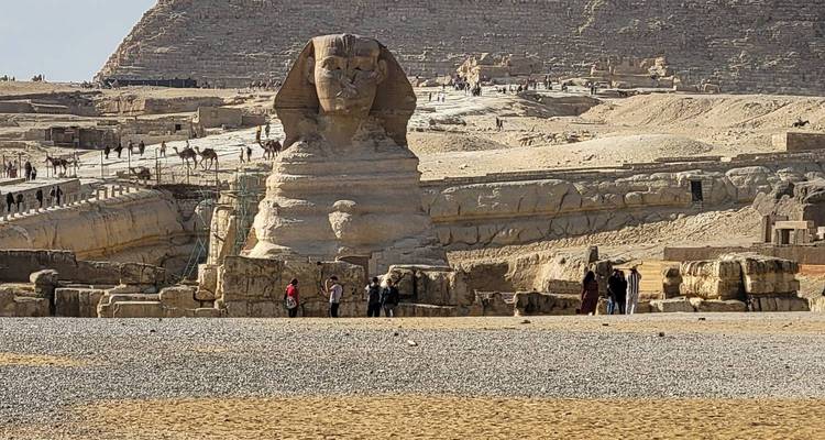 Wide shot of the Sphinx area with tourists and desert plateau in background