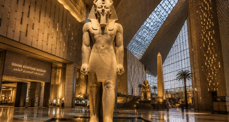 Grand Egyptian Museum interior featuring colossal pharaoh statue under glass roof.