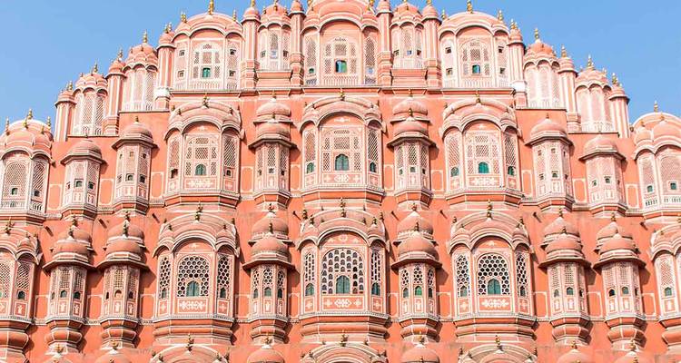 Façade de grès rose symétrique du Hawa Mahal sur un ciel bleu clair.