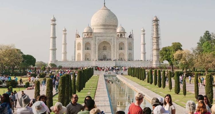 Iconic frontal view of the Taj Mahal with reflecting pool and landscaped gardens crowded with visitors.