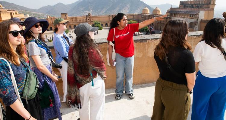 Local guide in red shirt points out Amber Fort features to an attentive tour group on the ramparts.