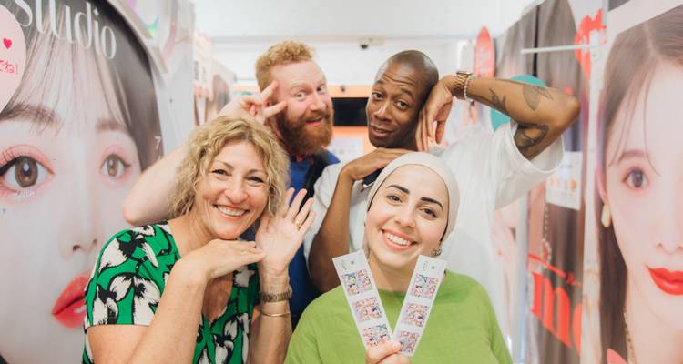 Un groupe joyeux adopte des poses amusantes à l'intérieur d'une cabine photo brillamment éclairée.