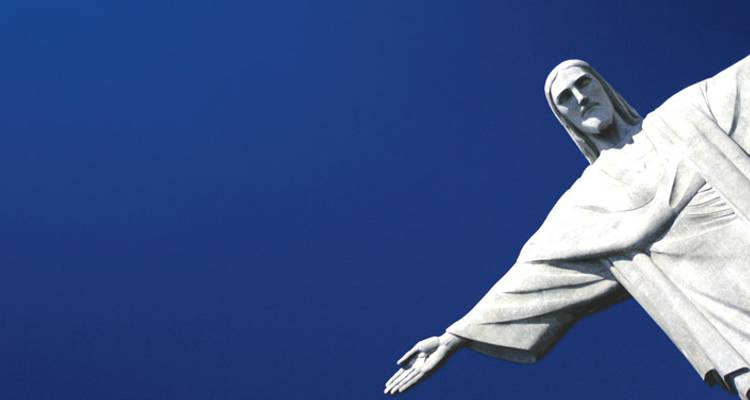 Iconic Christ the Redeemer statue stretching an arm against a deep blue sky.