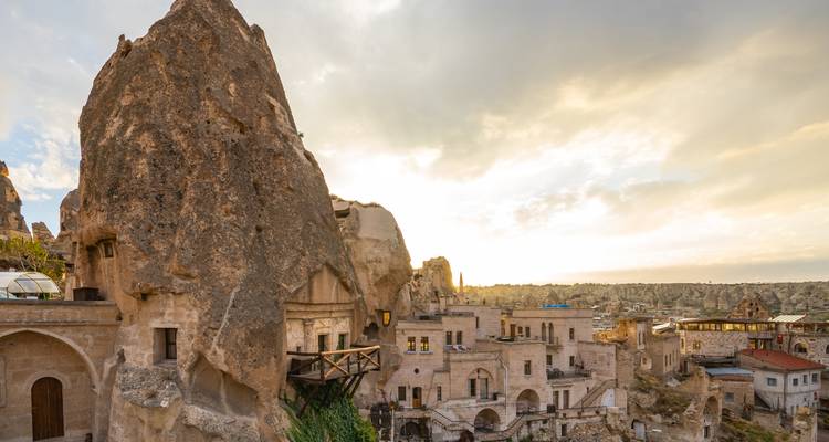Les habitations troglodytiques de Cappadoce baignées de lumière solaire et les imposantes formations rocheuses avec des maisons en pierre et des terrasses en contrebas.