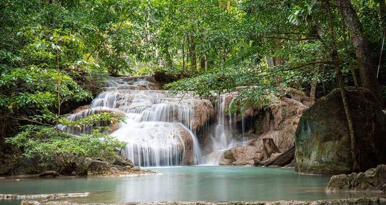 Multi-tiered turquoise pool and cascades of Erawan Waterfall surrounded by lush green jungle.