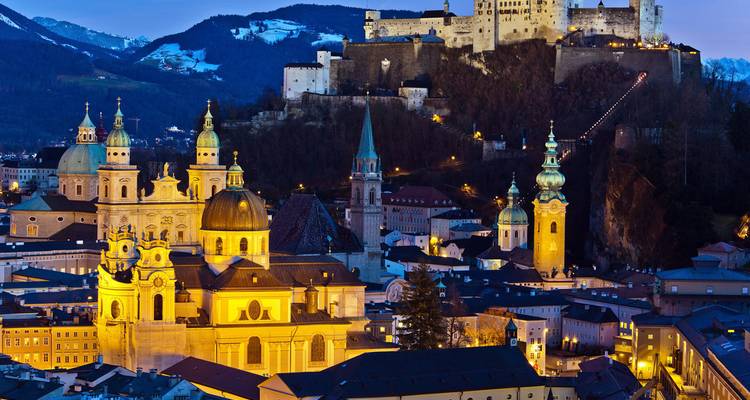 Night panorama of Salzburg’s baroque skyline beneath Hohensalzburg Fortress, illuminated against the Alps.