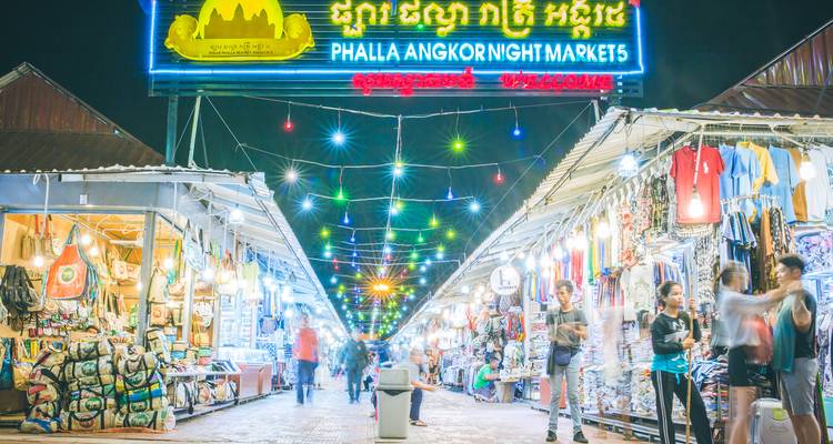 Hellglühender Phalla Angkor Nachtmarkt mit Leuchtreklame und Einkäufern, die zwischen den Ständen umhergehen