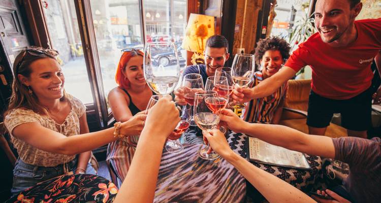 Group of friends toast with glasses of wine inside a cozy urban bar