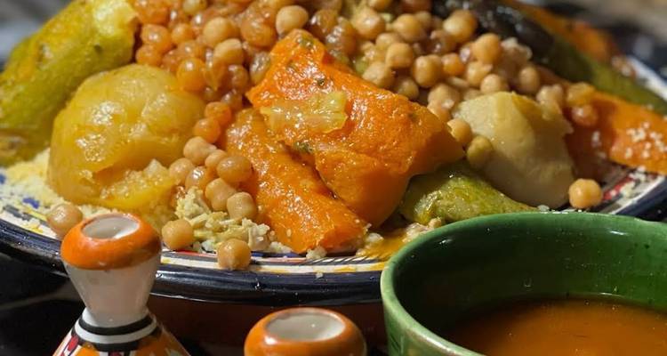 Nahaufnahme eines farbenfrohen Couscous-Gerichts mit Kichererbsen und Gemüse als Topping
