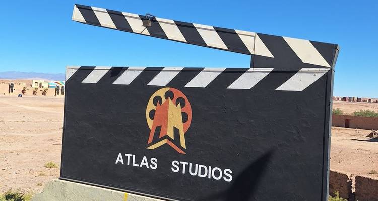 Panneau d'affichage extérieur en bardage affichant le logo d'Atlas Studios dans le désert sous un ciel bleu dégagé.