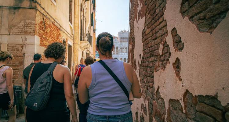 Tourists wander through a narrow brick alleyway in an old European city.