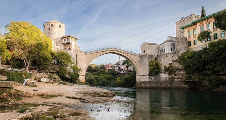 Historic stone arch bridge spanning a river between medieval buildings and towers