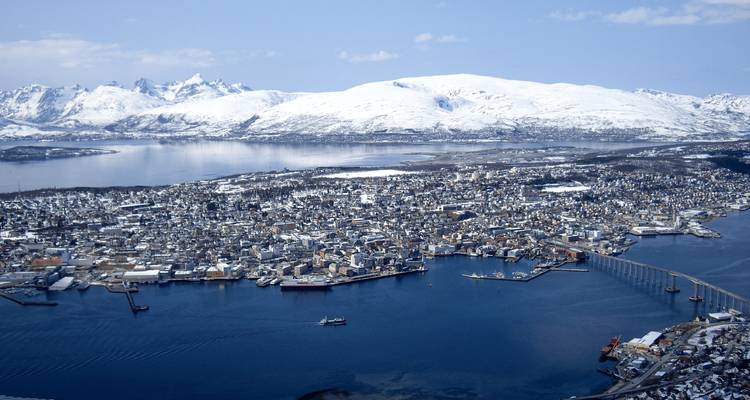 Vue panoramique aérienne de l'île de la ville de Tromsø entourée de fjords et de pics enneigés.