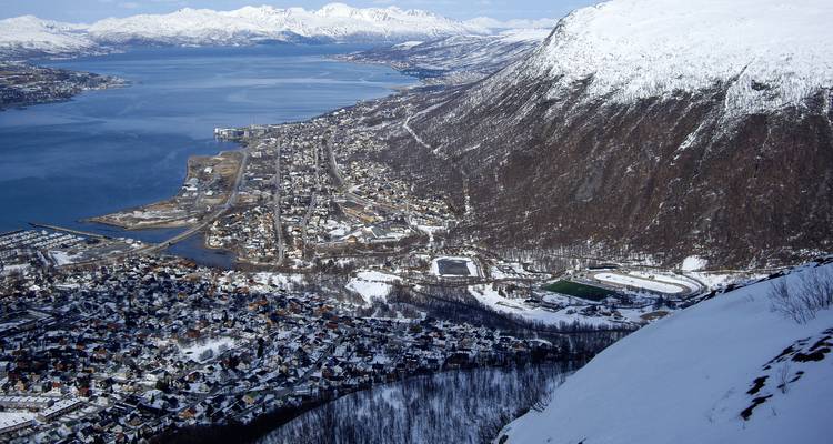Vue panoramique élevée sur une ville côtière enneigée nichée entre les eaux des fjords et les montagnes.