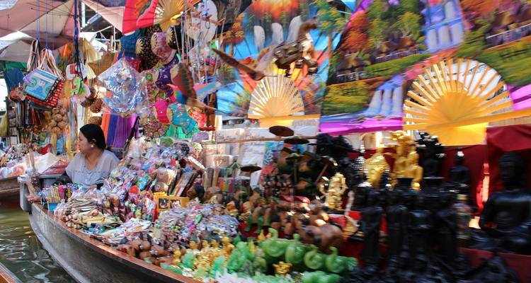 Vendor in a floating market boat selling vibrant souvenirs and trinkets piled high.