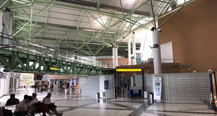 Spacious modern airport terminal interior with passengers waiting on benches.