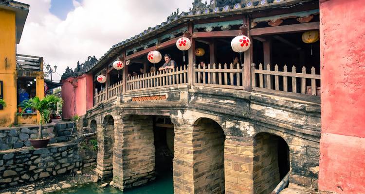 Traditionele Japanse overdekte brug in het oude stadje Hoi An met een bezoeker die naar buiten kijkt van binnenuit.
