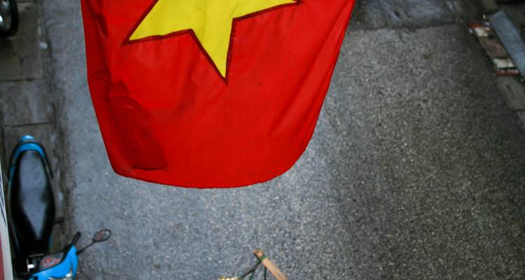 Close-up van de Vietnamese nationale vlag met een gele ster die wappert boven een grijze straat
